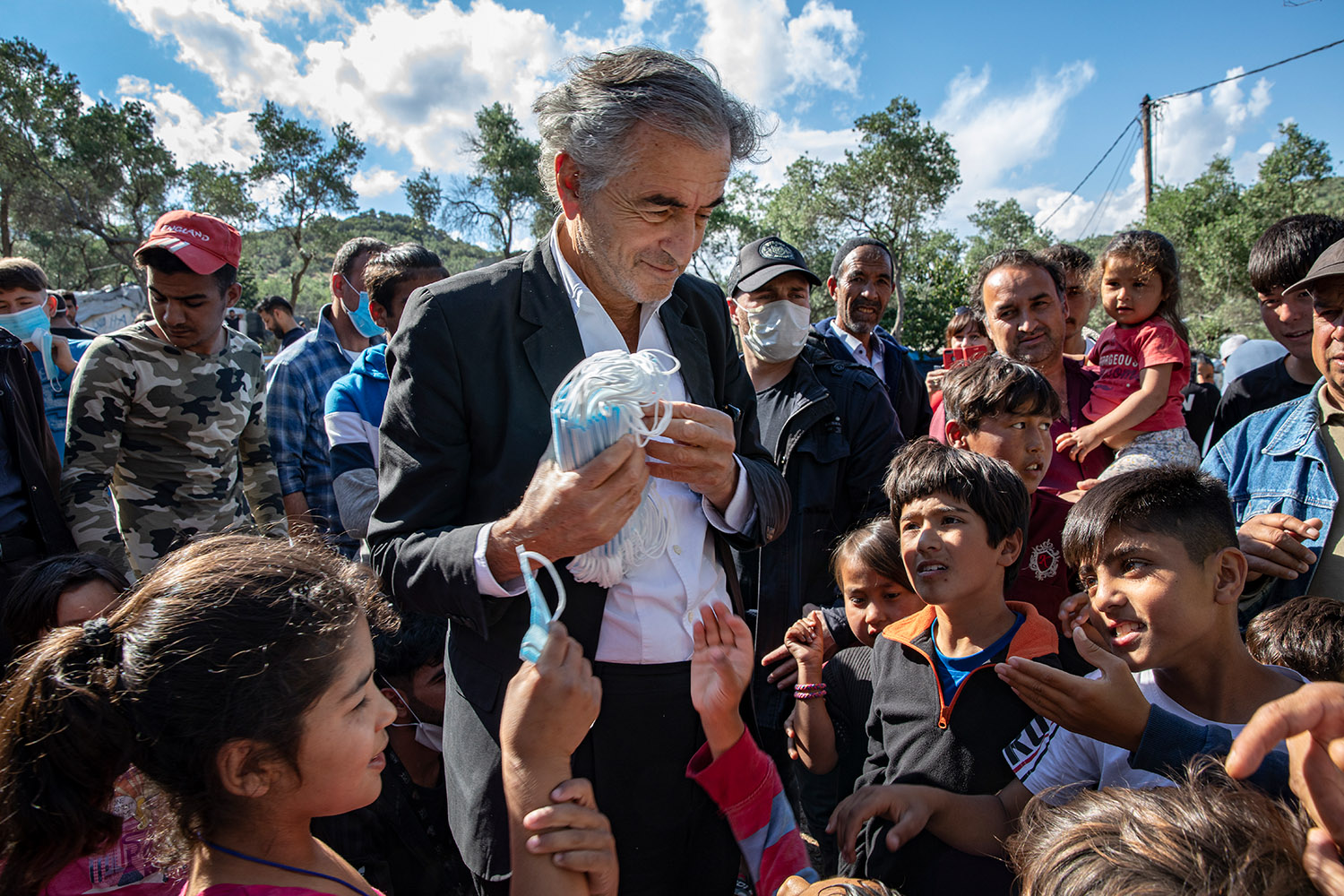 Bernard-Henri Lévy distribue des masques aux enfants réfugiés.