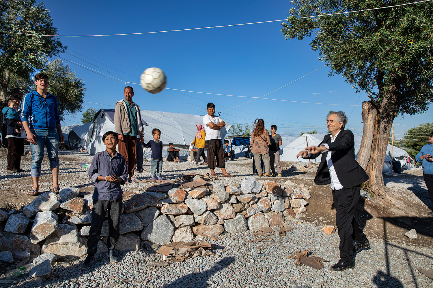 Bernard-Henri Lévy joue au ballon avec les enfants réfugiés de Moria.