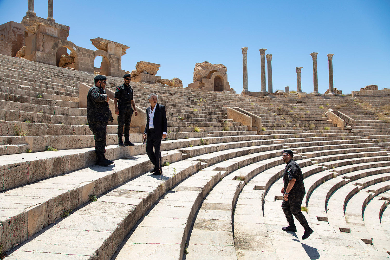 Bernard-Henri Lévy escorté dans les ruines de la cité antique de Leptis Magna, dans l'amphithéâtre.