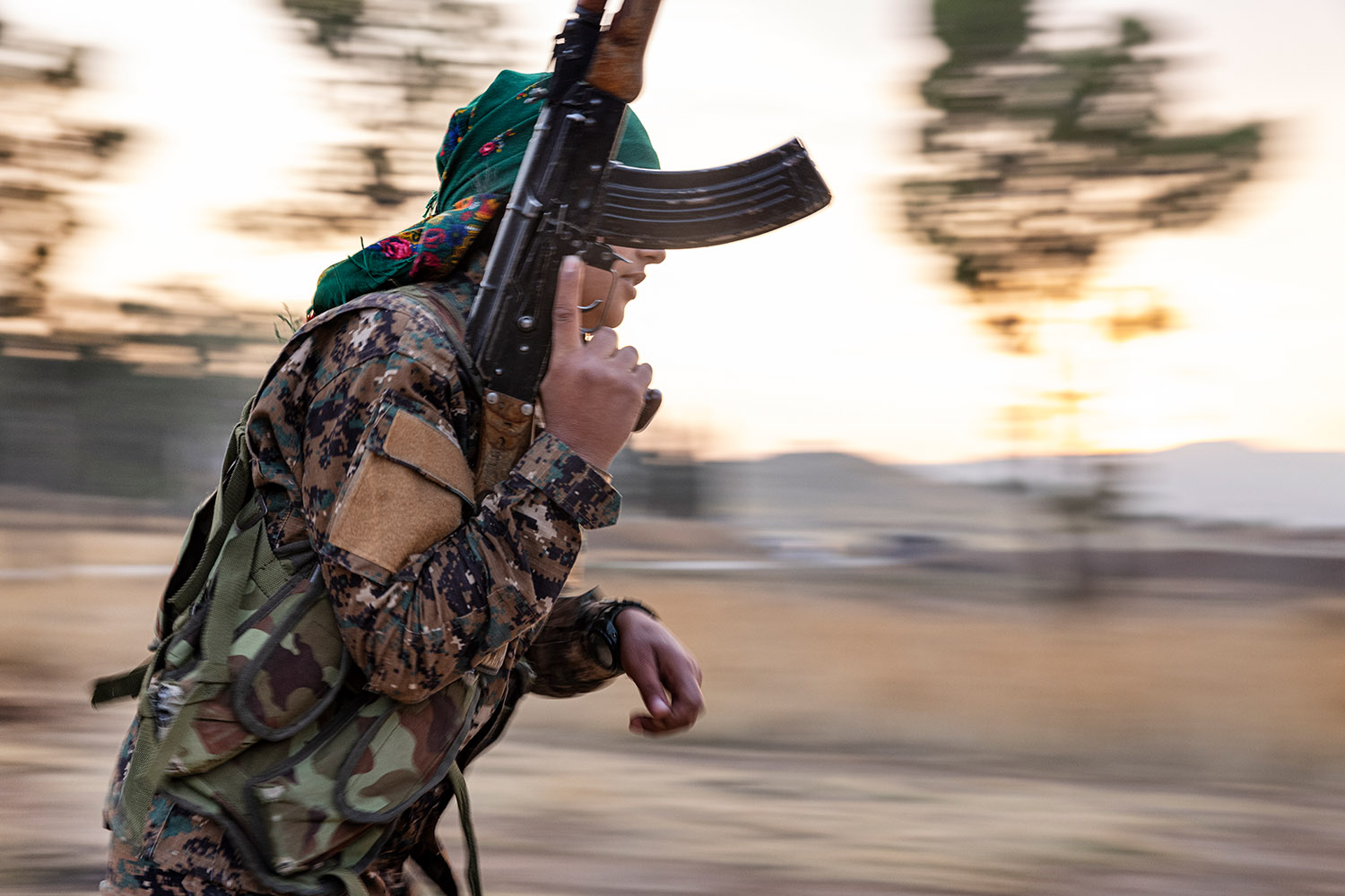 Une combattante kurde court fusil à la main.