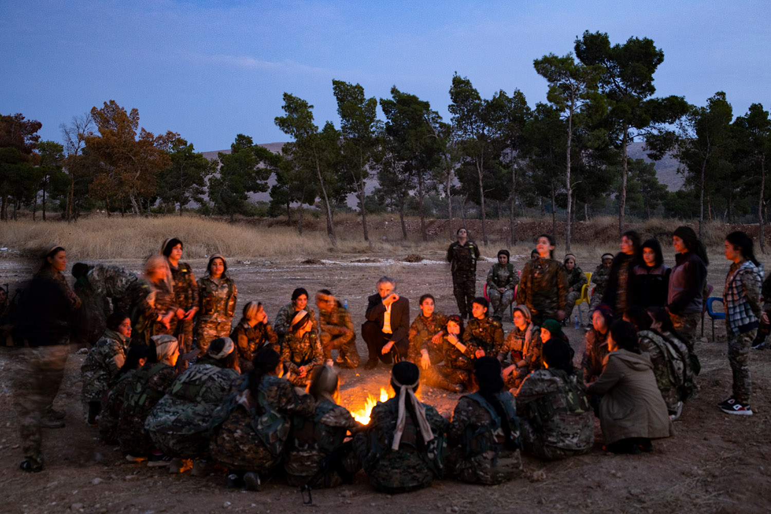 Bernard-Henri Lévy et les combattantes du Rojava, autour d'un feu à la tombée du jour.