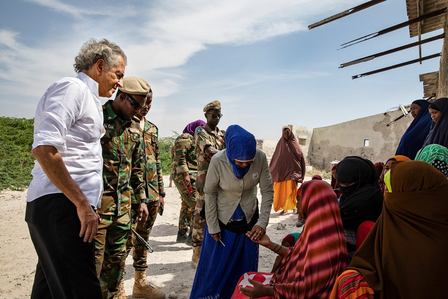 Bernard-Henri Lévy parle avec les femmes de Jazira, elles portent des abayas multicolores, il est accompagné par des militaires.