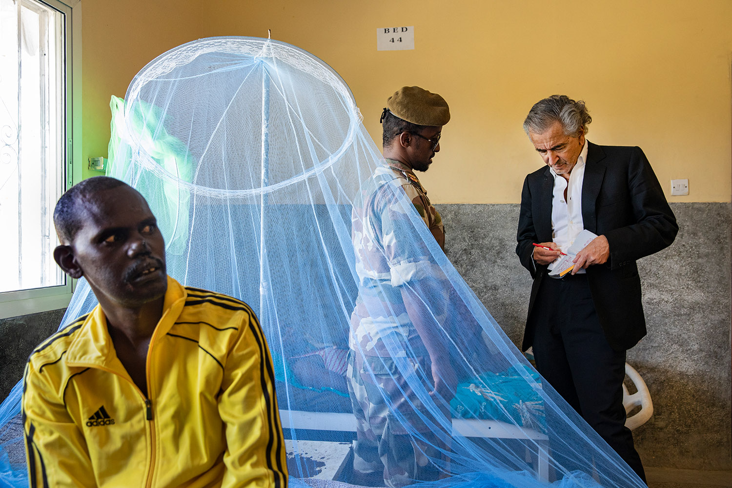 Bernard-Henri Lévy à l’hôpital de Mogadiscio, il prend des hommes auprès d'un militaire qui lui parle.
