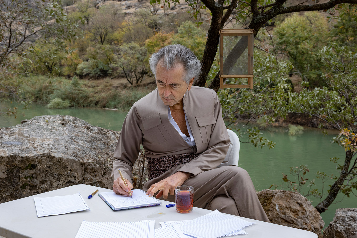 À Barzan au Kurdistan irakien en novembre 2020, Bernard-Henri Lévy écrit dans un carnet, près d'une rivière.