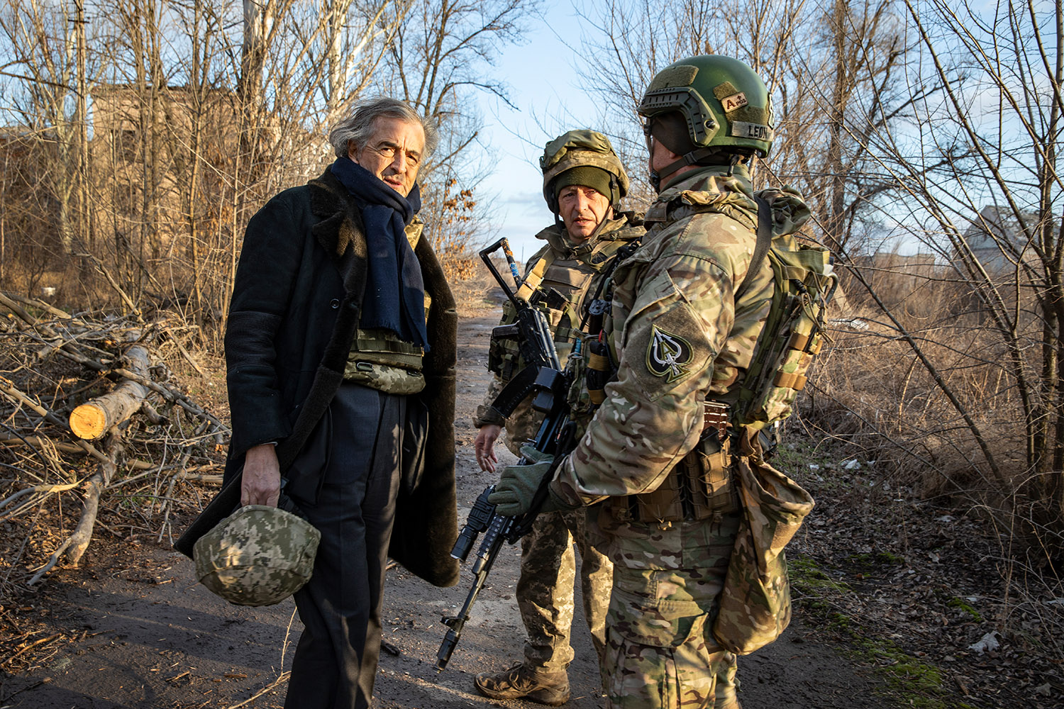 Bernard-Henri Lévy avec deux militaires en uniformes, en plein hiver. BHL porte son casque de soldat à la main.