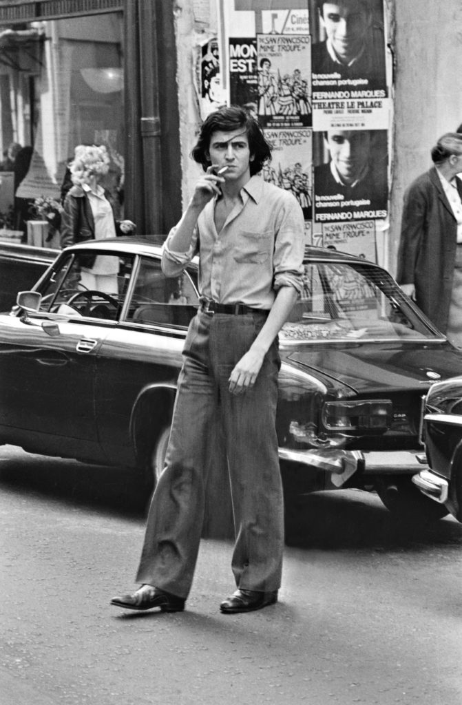 Bernard-Henri Lévy traverse la rue en fumant une cigarette.