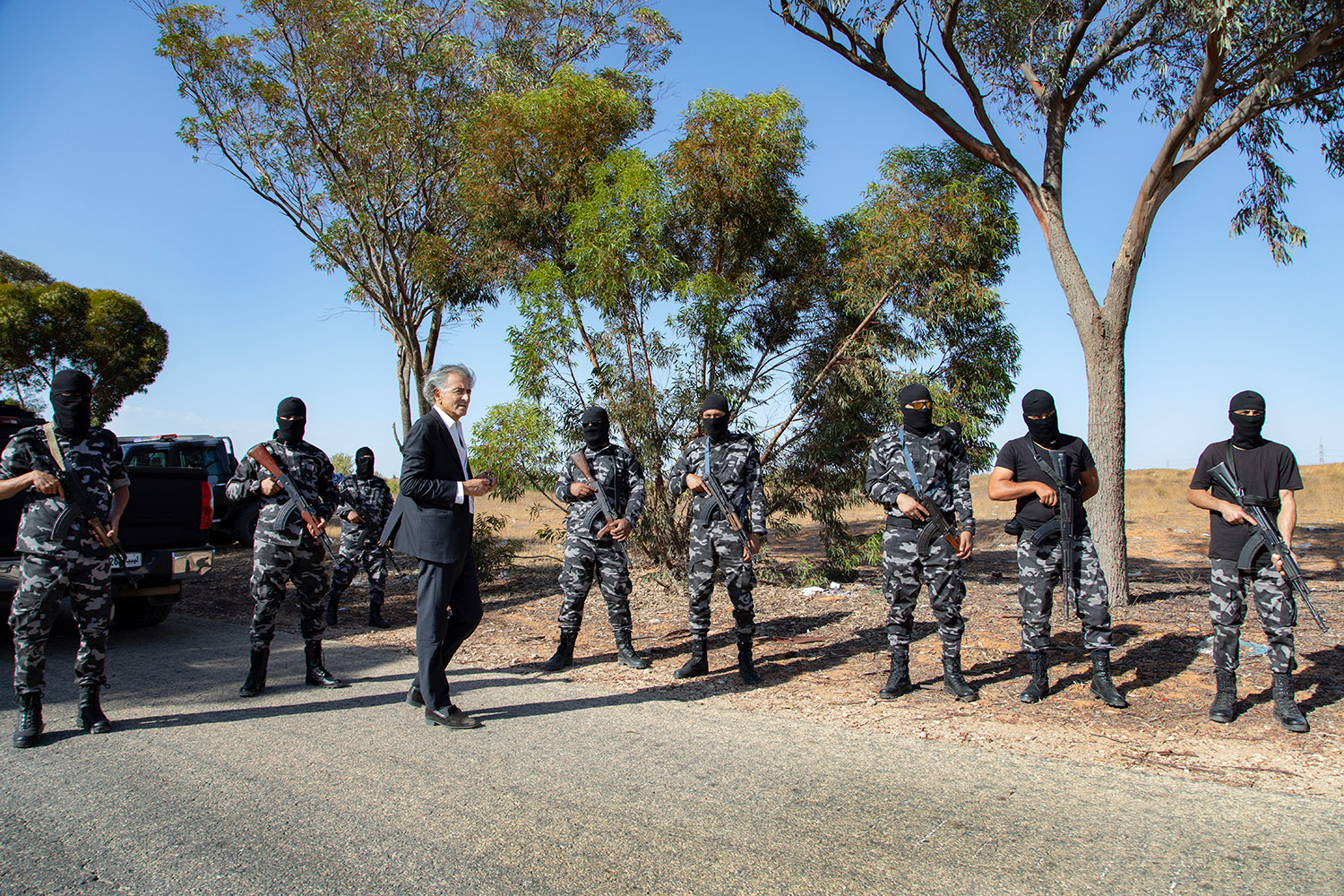 À Tarhouna au mois de Juillet 2020. Bernard-Henri Lévy est sur une route libyenne entouré de militaires qui constituent l'escorte de son équipe.