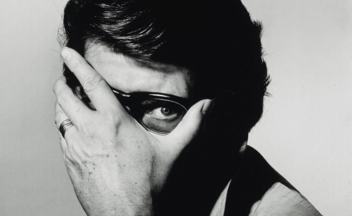 Portrait réalisé par Irving Penn en 1983 en noir et blanc d'Yves Saint Laurent qui dissimule son visage derrière sa main.