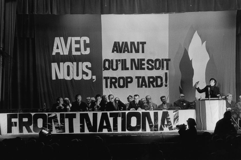 Photo en noir et blanc, le 7 novembre 1972, Jean-Marie Le Pen lors de la première réunion publique du Front national à La Mutualité en présence notamment de Pierre Bousquet, François Brigneau, Roger Holeindre et Alain Robert.