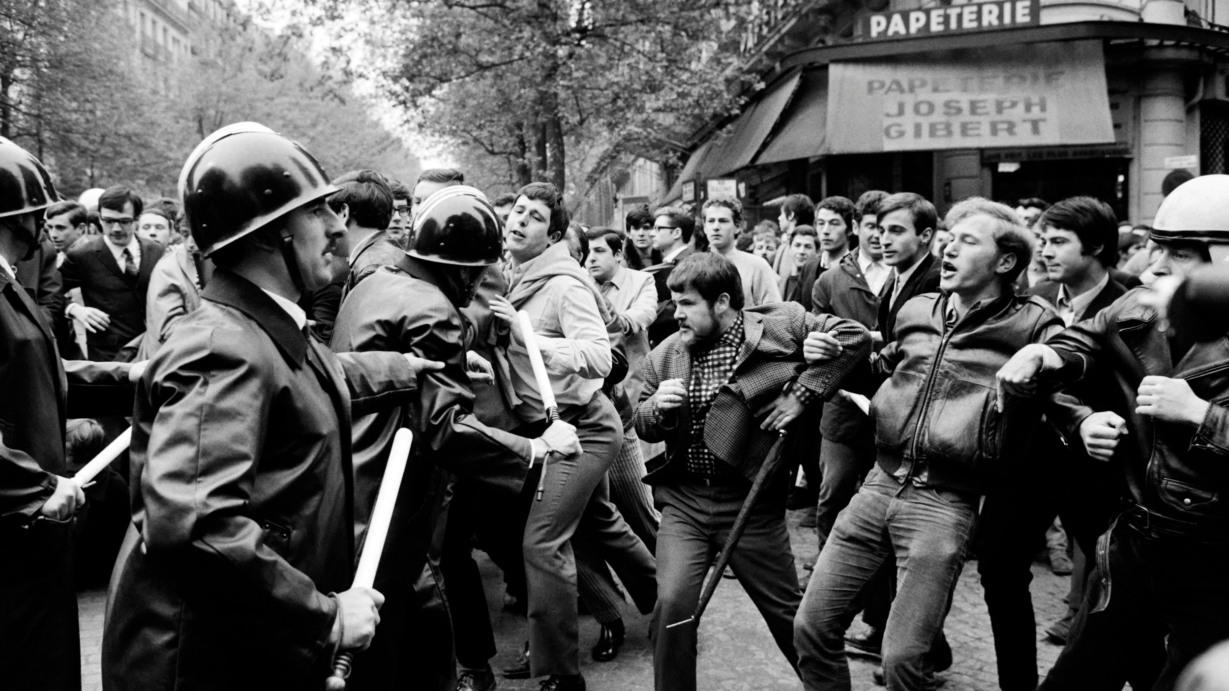 Photo en noir et blanc prise le Le 6 mai 1968, des étudiants et des protestataires font face à la police, à Paris, devant la librairie Joseph Gibert près de la Sorbonne.