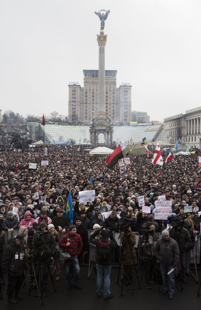Foule devant la tribune de la place Maidan, Kiev le 2 mars 2014. La foule porte des drapeaux et des pencartes.