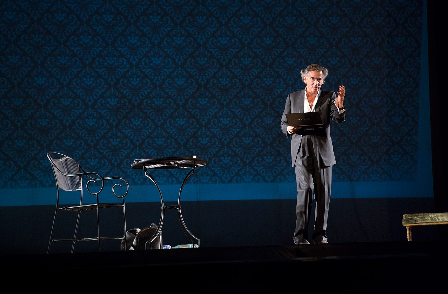 Bernard-Henri Lévy interprète sa pièce « Hôtel Europe » à l'Opéra d'Odessa. Il tient son ordinateur dans une main et s'adresse à la salle.