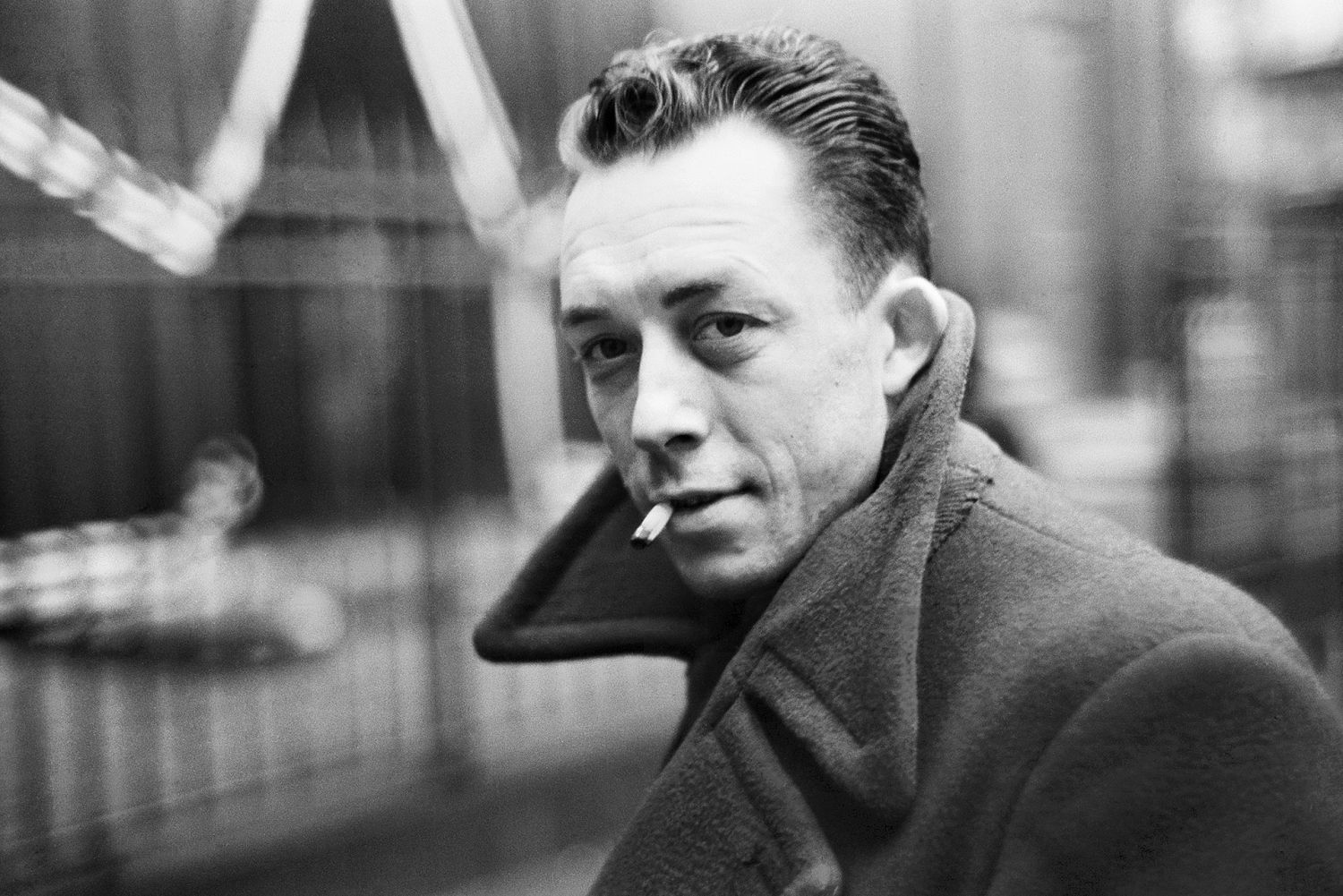 Portrait en noir et blanc de l'écrivain et philosophe Albert Camus, qui fume une cigarette
