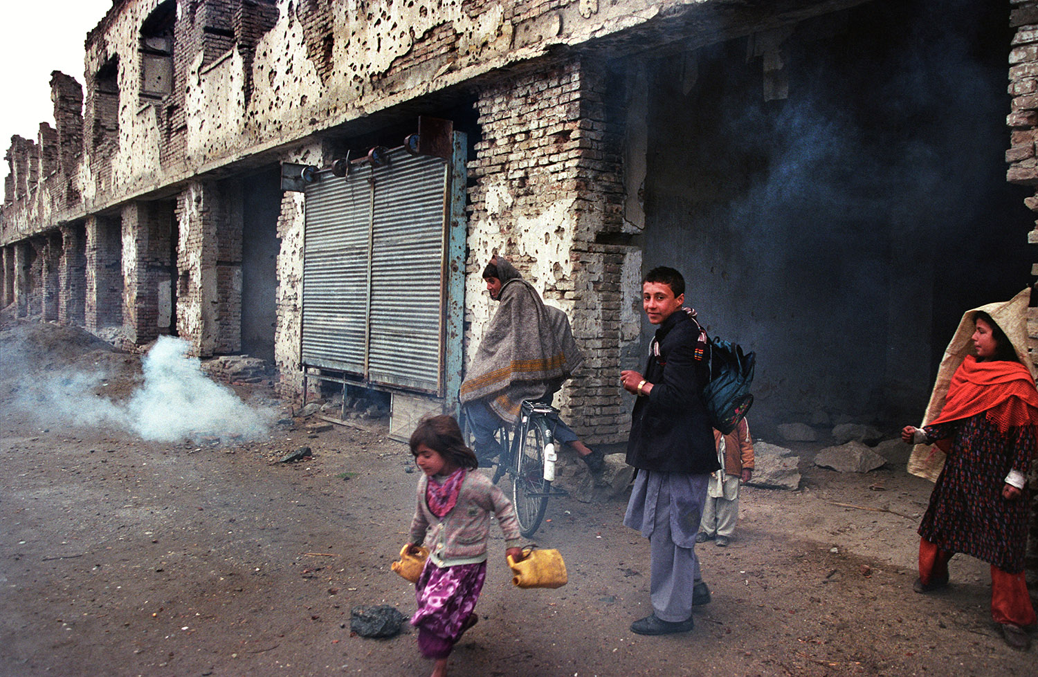 Dans une rue de Kaboul, les batiments sont presque en ruines. Il y a des enfants afghans dans la rue.
