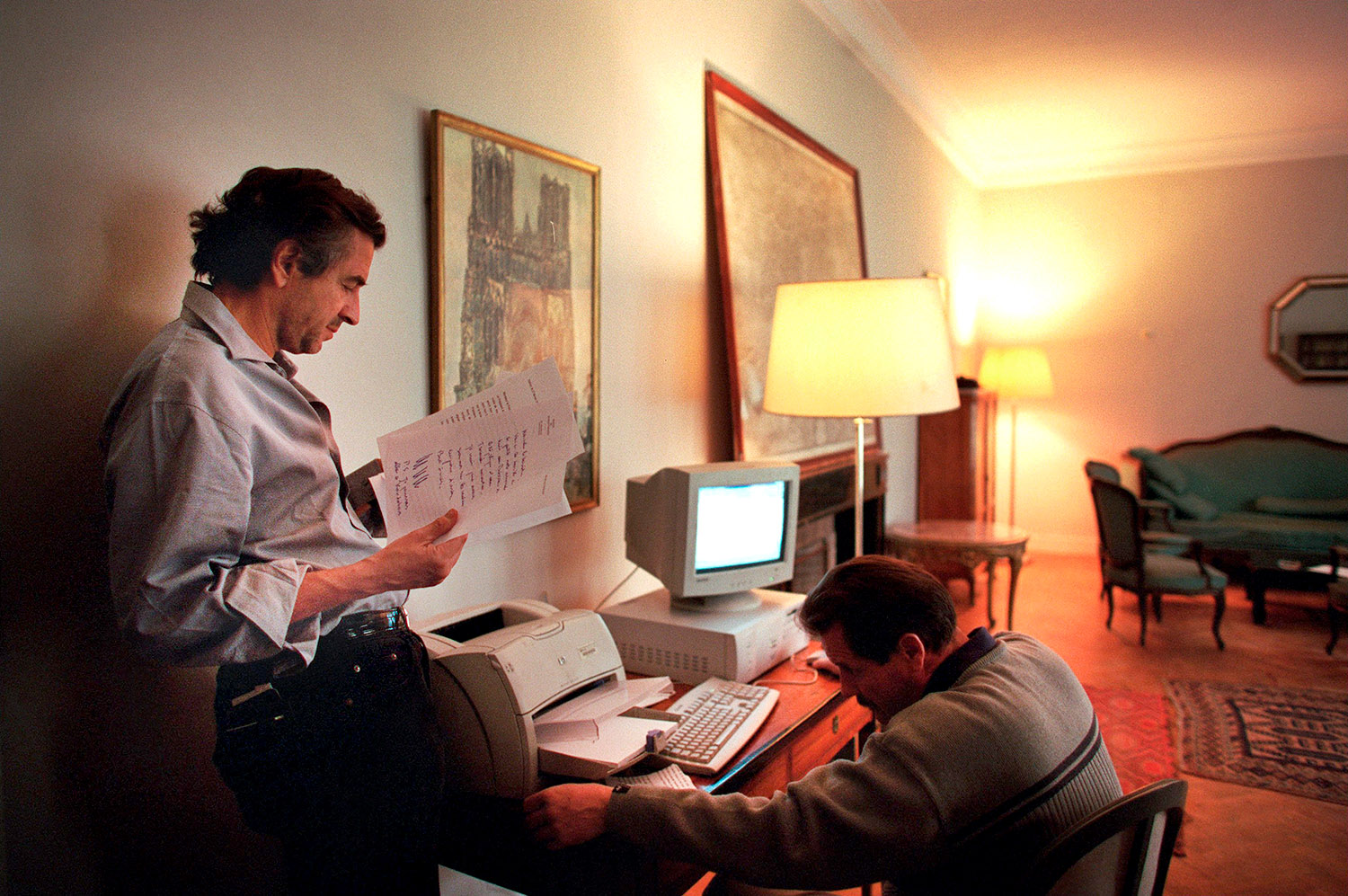 Bernard-Henri Lévy à l'ambassade France, à Kaboul. Bernard-Henri Lévy consulte des papiers près d'un bureau avec un ordinateur et un fax devant lequel est assis un homme.