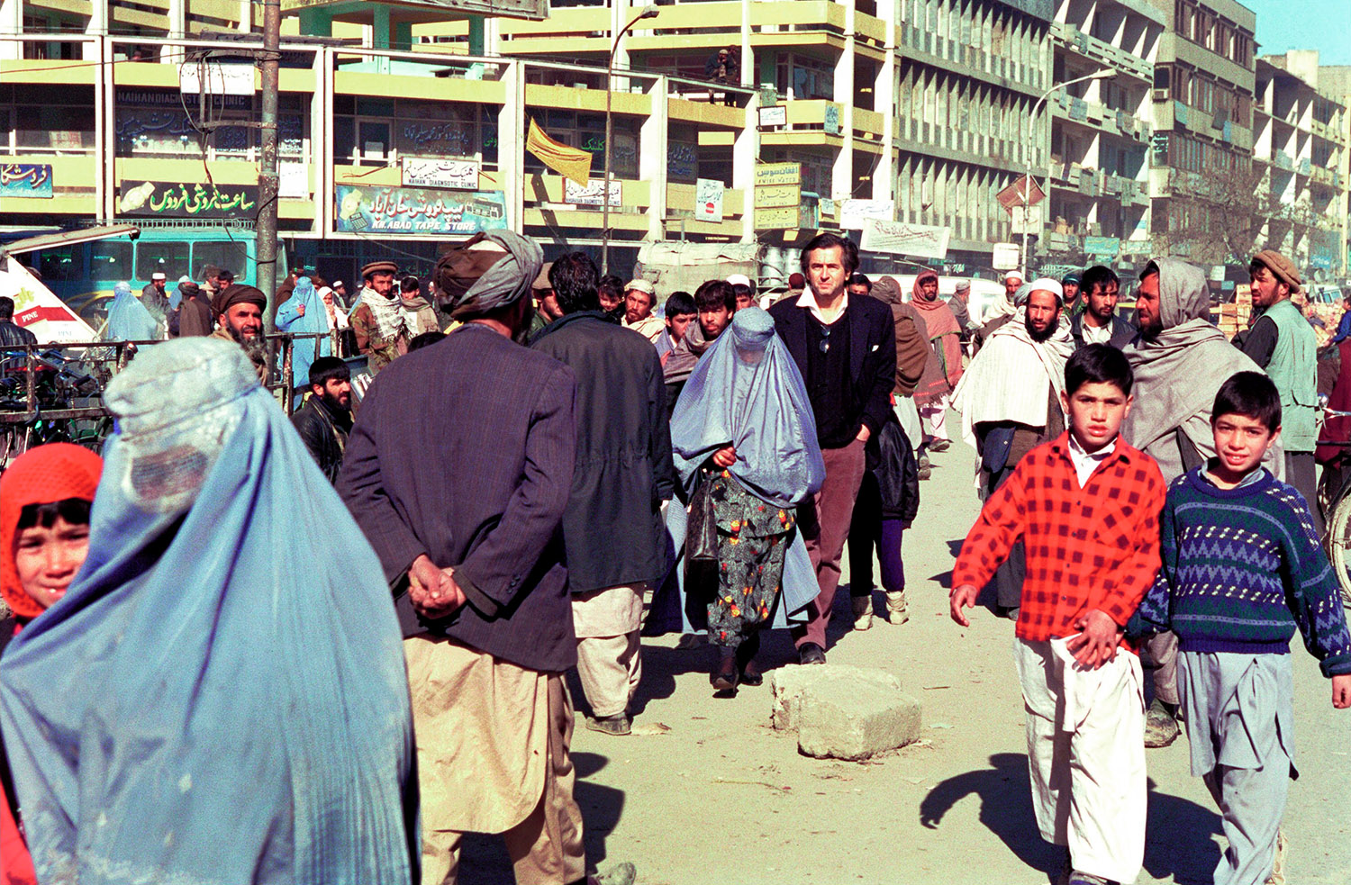 Bernard-Henri Lévy marche dans les rues de Kaboul au milieu du peuple afghan. Les femmes portent des burquas