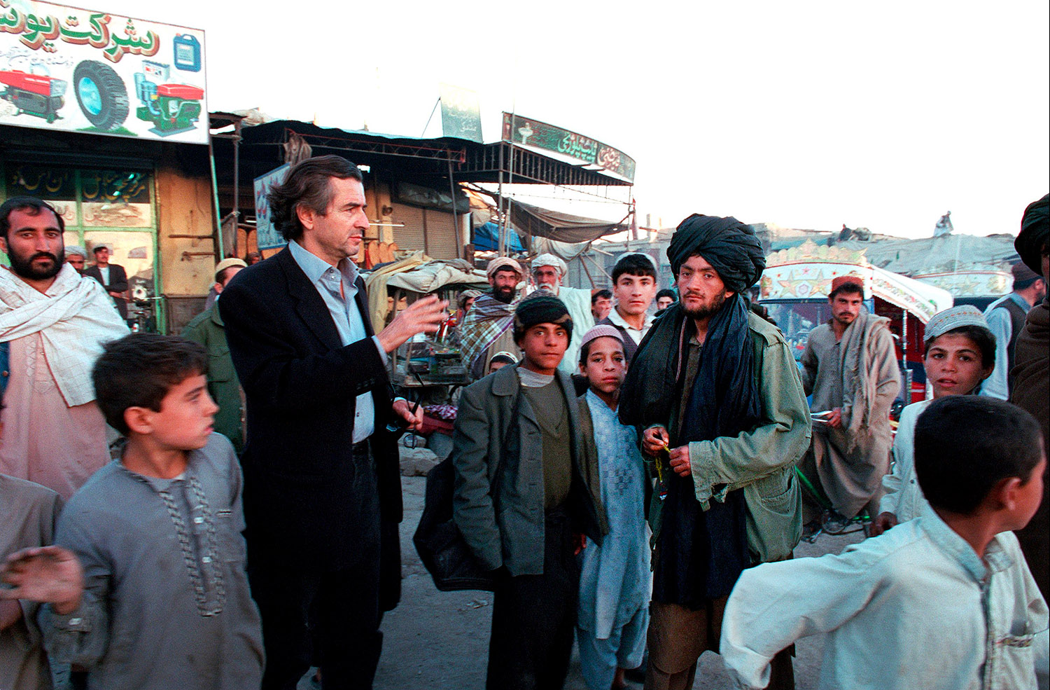 Bernard-Henri Lévy parle avec des afghans dans une rue de Kandahar