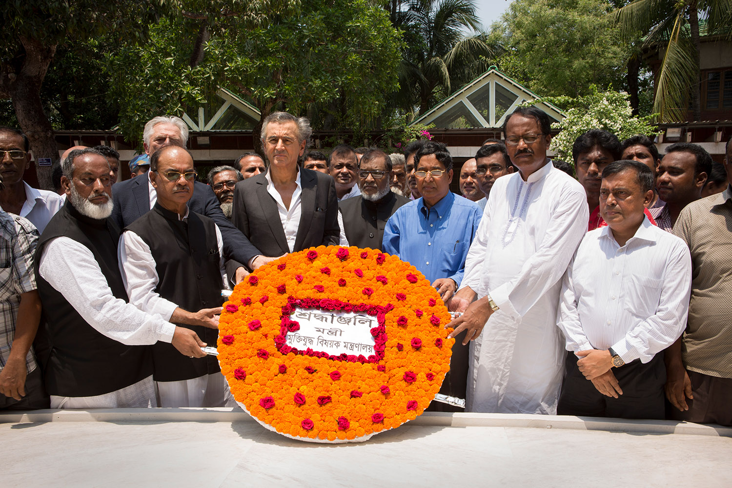 Bernard-Henri Lévy lors de l'hommage à Mujibur Rahman, ancien Premier Ministre du Bangladesh, Gopalganj. Le philosophe est entouré par des bengladeshis qui portent une couronne de fleurs.