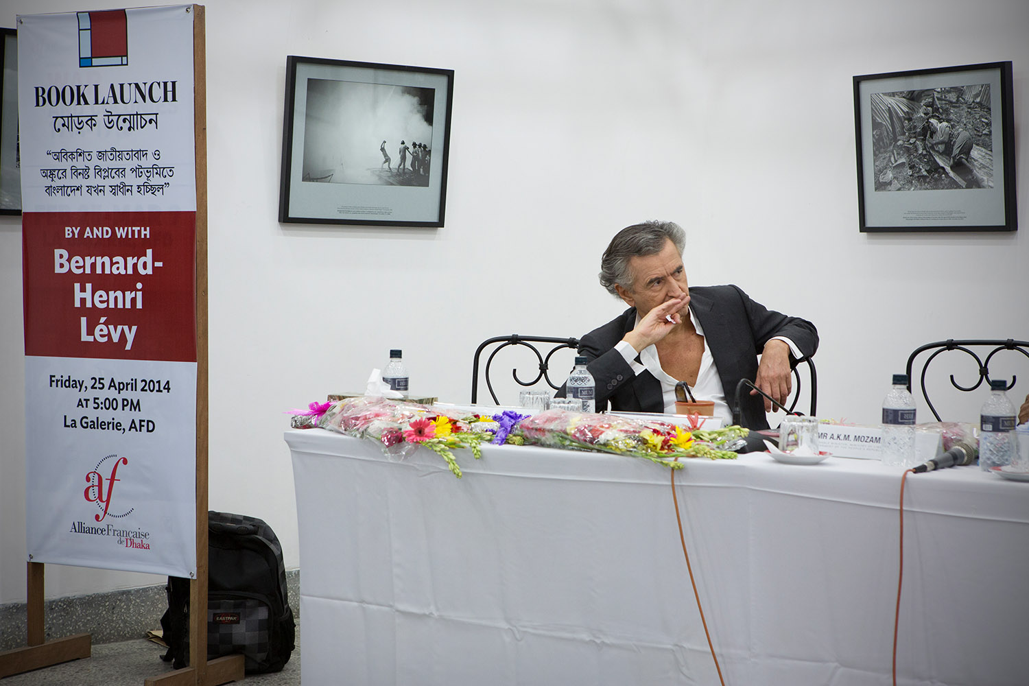 Bernard-Henri Lévy est assis derrière une table de conférence à l'Alliance française de Dacca.