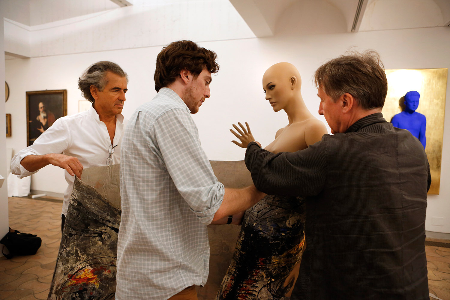 Bernard-Henri Lévy, Tancrède Hertzog et François Letailleur préparent l'installation d'une toile de Giuseppe Pinot-Gallizio sur un mannequin en plastique
