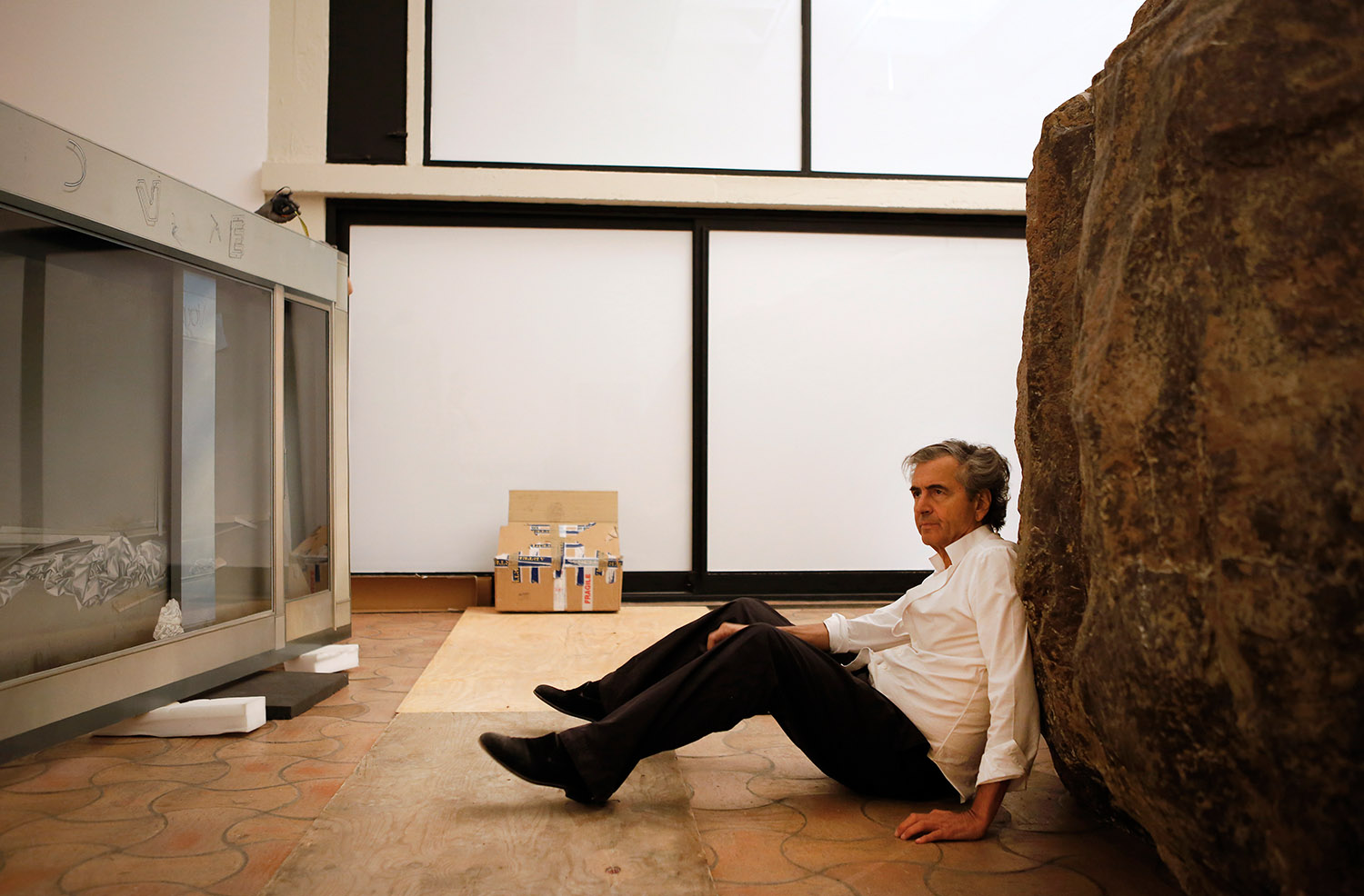 Bernard-Henri Lévy, assis par terre, est adossé à la "Caverne de Platon" de Huang Yong Ping.