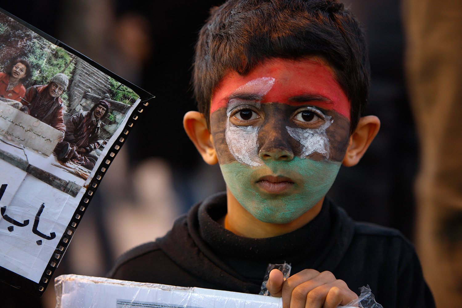Visage d'un enfant qui porte sur son visage un maquillage qui représente le drapeau de la Libye.