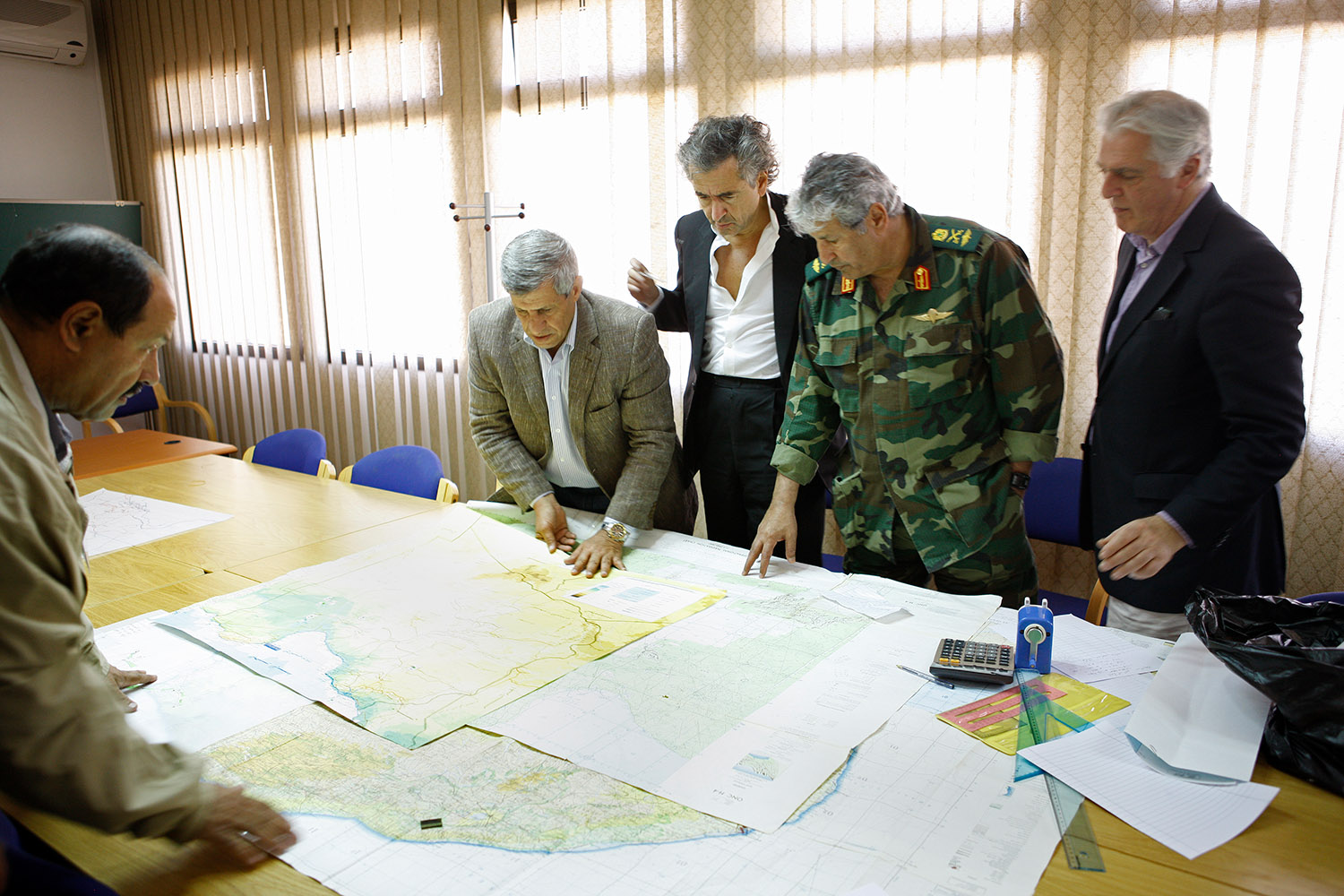 Bernard-Henri Lévy et Gilles Hertzog à Benghazi. Ils regardent des plans militaires autour d'une table avec des militaires en uniformes.