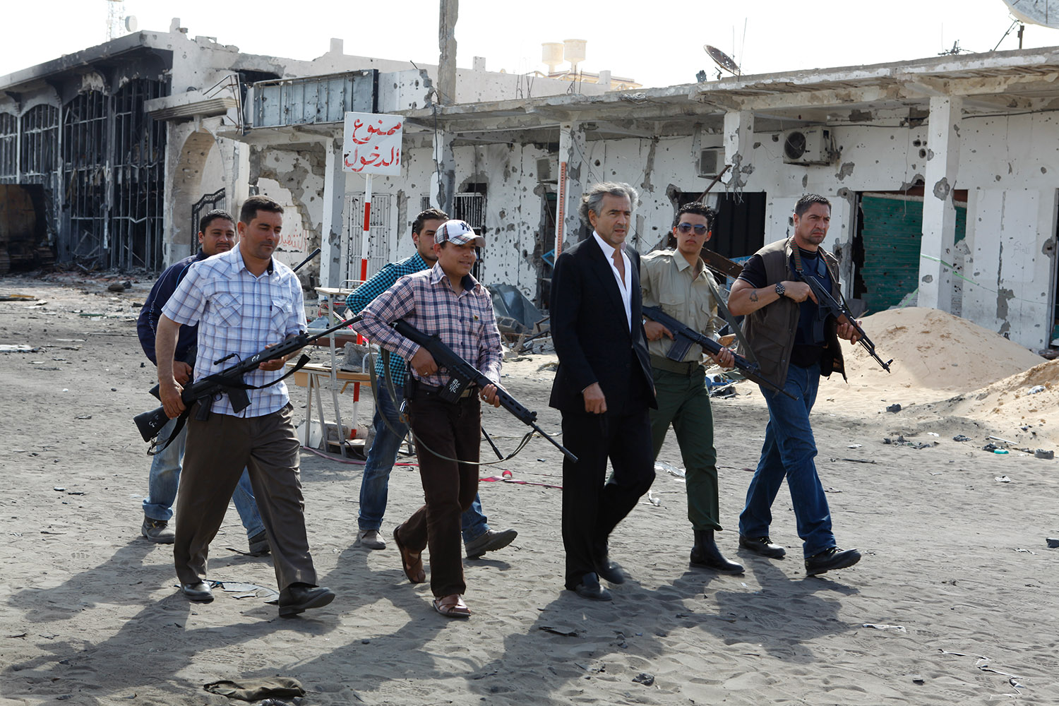 Bernard-Henri Lévy escorté par des hommes armés dans les rues de Misrata déserte en Libye.
