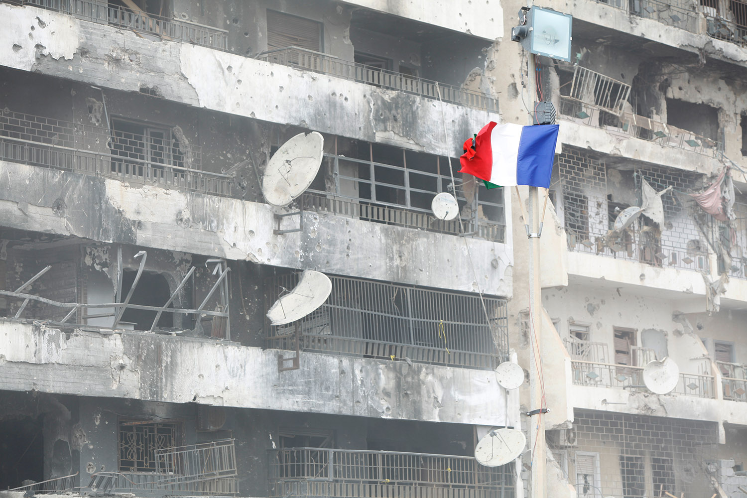 Le drapeau français flotte au milieu des ruines de la ville de Misrata. Détail d'un immeuble brûlé, bombardé, qui a subi le feu des chars de Kadhafi.