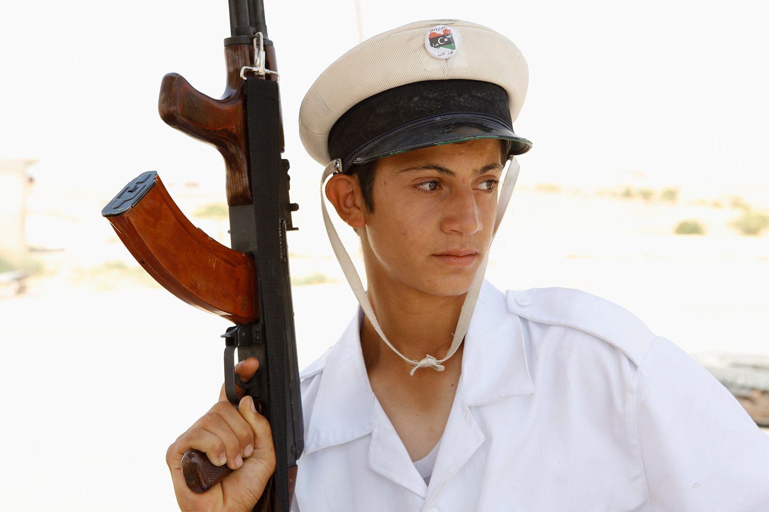 Portrait d'un jeune rebelle libyen, il porte un képi blanc et une mitraillette.