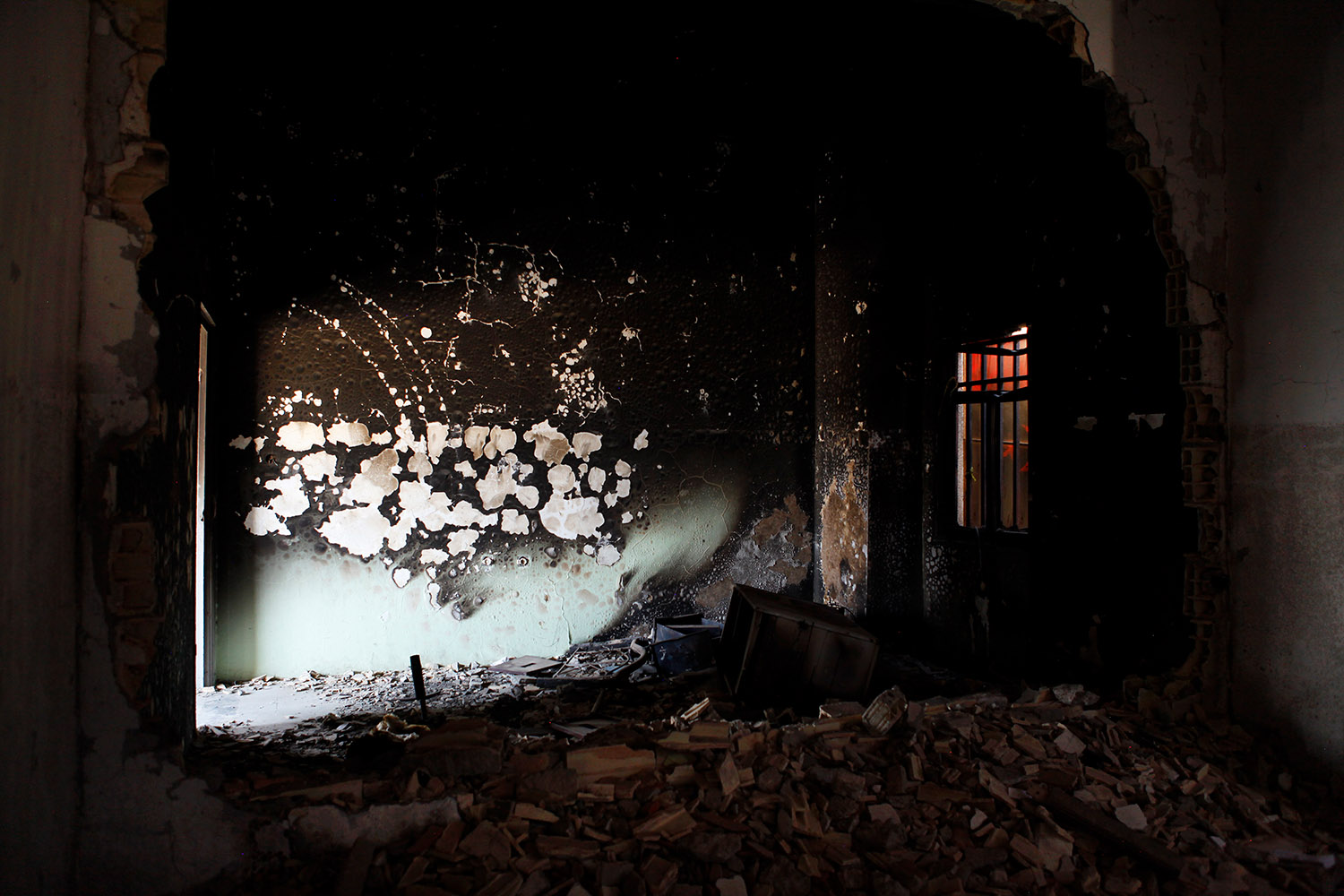 Les décombres de la ville de Tobrouk. On voit des débris, des murs noircis par le feu et des impacts de balles dans la pierre.