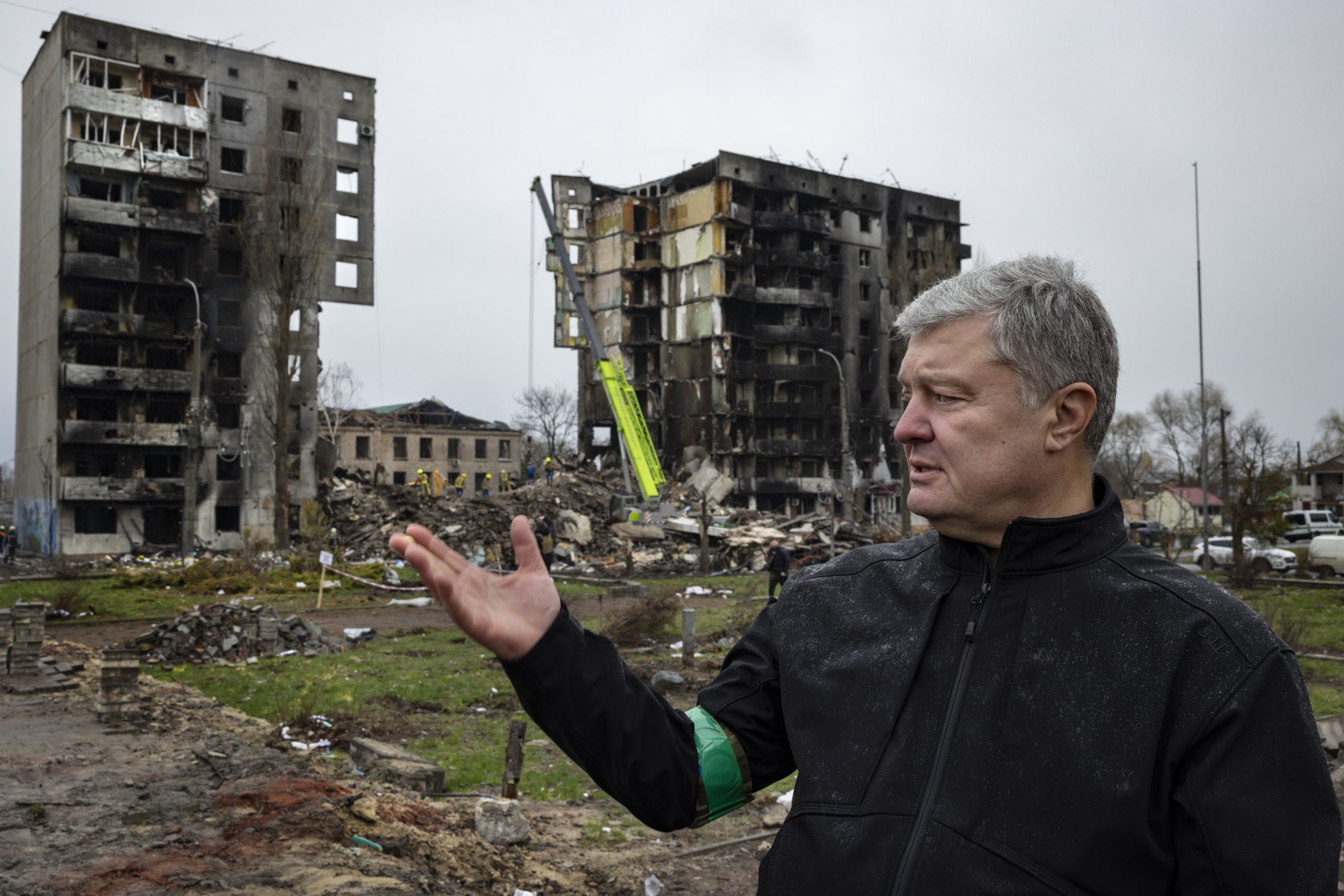 Boutcha avec Petro Porochenko, qui semble montrer quelque chose avec sa main. Derrière lui on voit des immeubles détruits, calcinés.