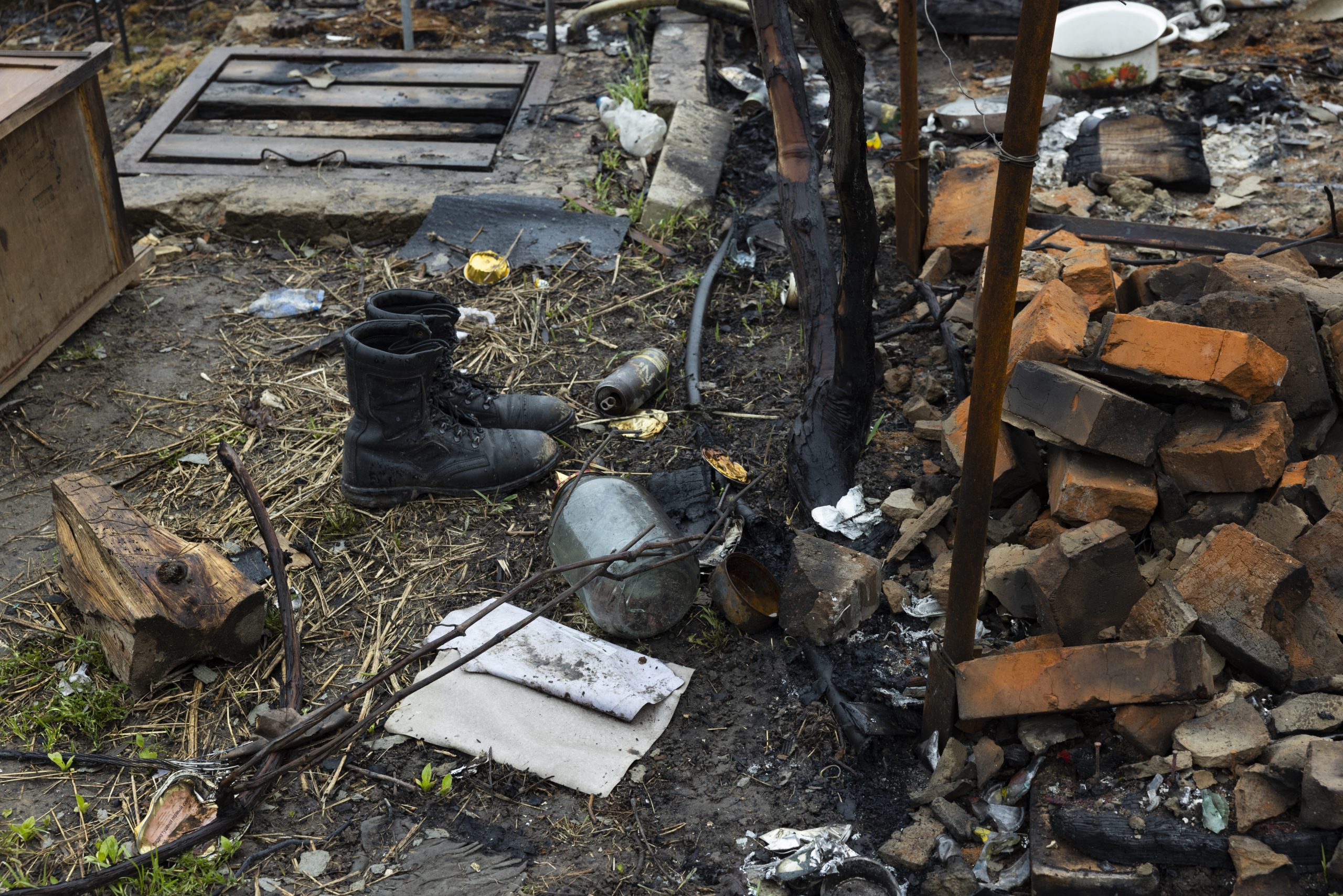 Au milieu des décombres, au pied d'un arbre brûlé, une paire de bottes échangée contre celles d'un Ukrainien tué..