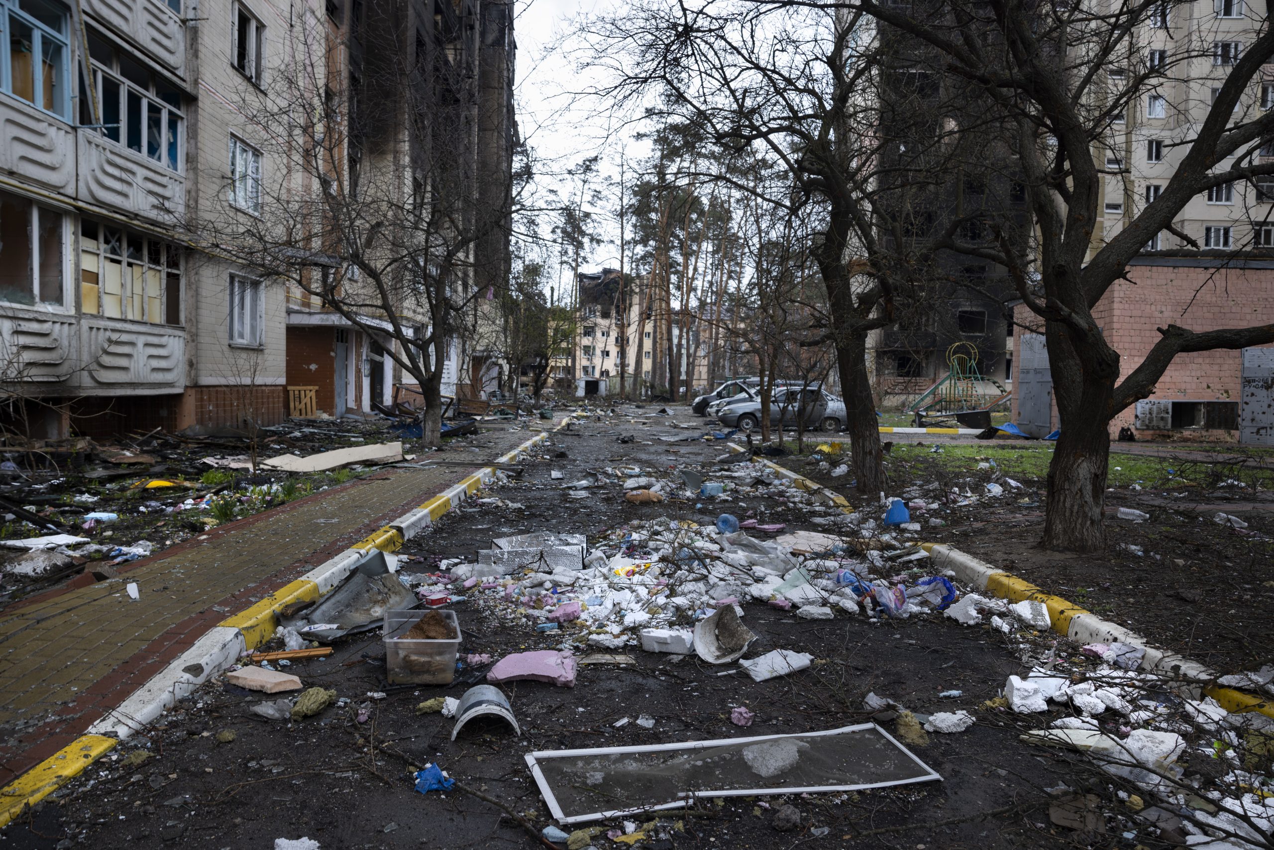 Dans une rue de la ville de Boutcha en Ukraine, les immeubles sont noirs après des incendies. Le sol est recouvert de débris.