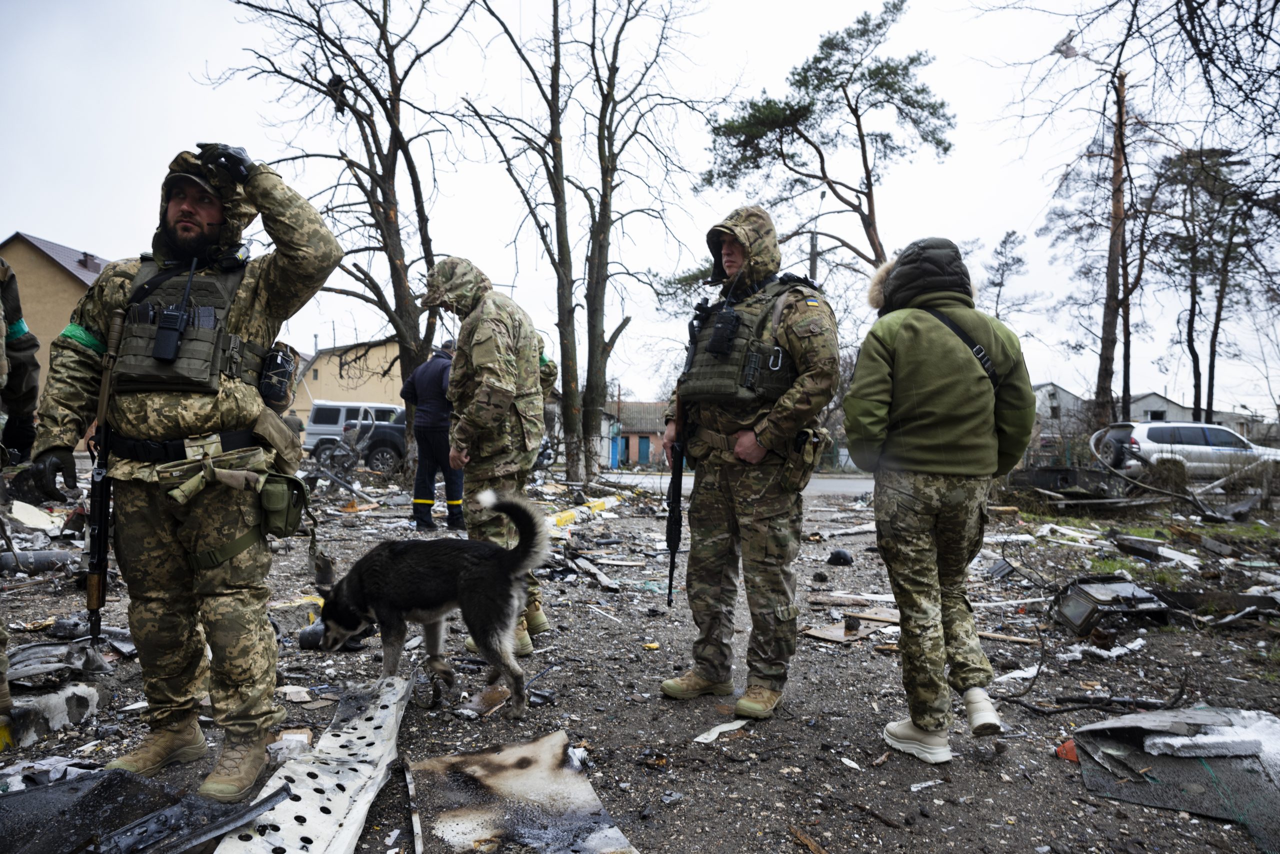Des militaires avec un chien au milieu des décombres causés par les bombardements à Boutcha en Ukraine.