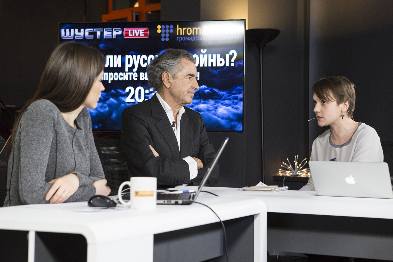 Interview de Bernard-Henri Lévy par deux femmes journalistes assises à droite et à gauche du philosophe.