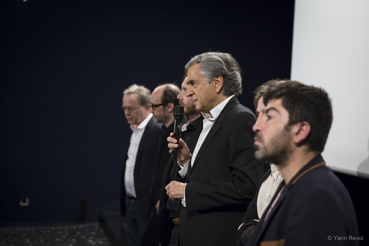 Bernard-Henri Lévy présente son film « Peshmerga », il parle dans un micro entouré de son équipe.