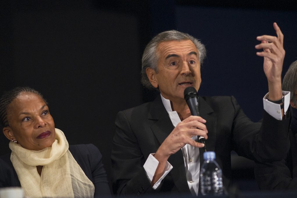 Christiane Taubira regarde Bernard-Henri Lévy qui parle dans un micro.