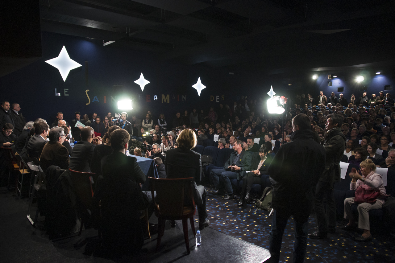 vue d'une salle de cinéma comble avec du public, des photographes, tournées vers des écrivains assis derrière une table pour un séminaire.