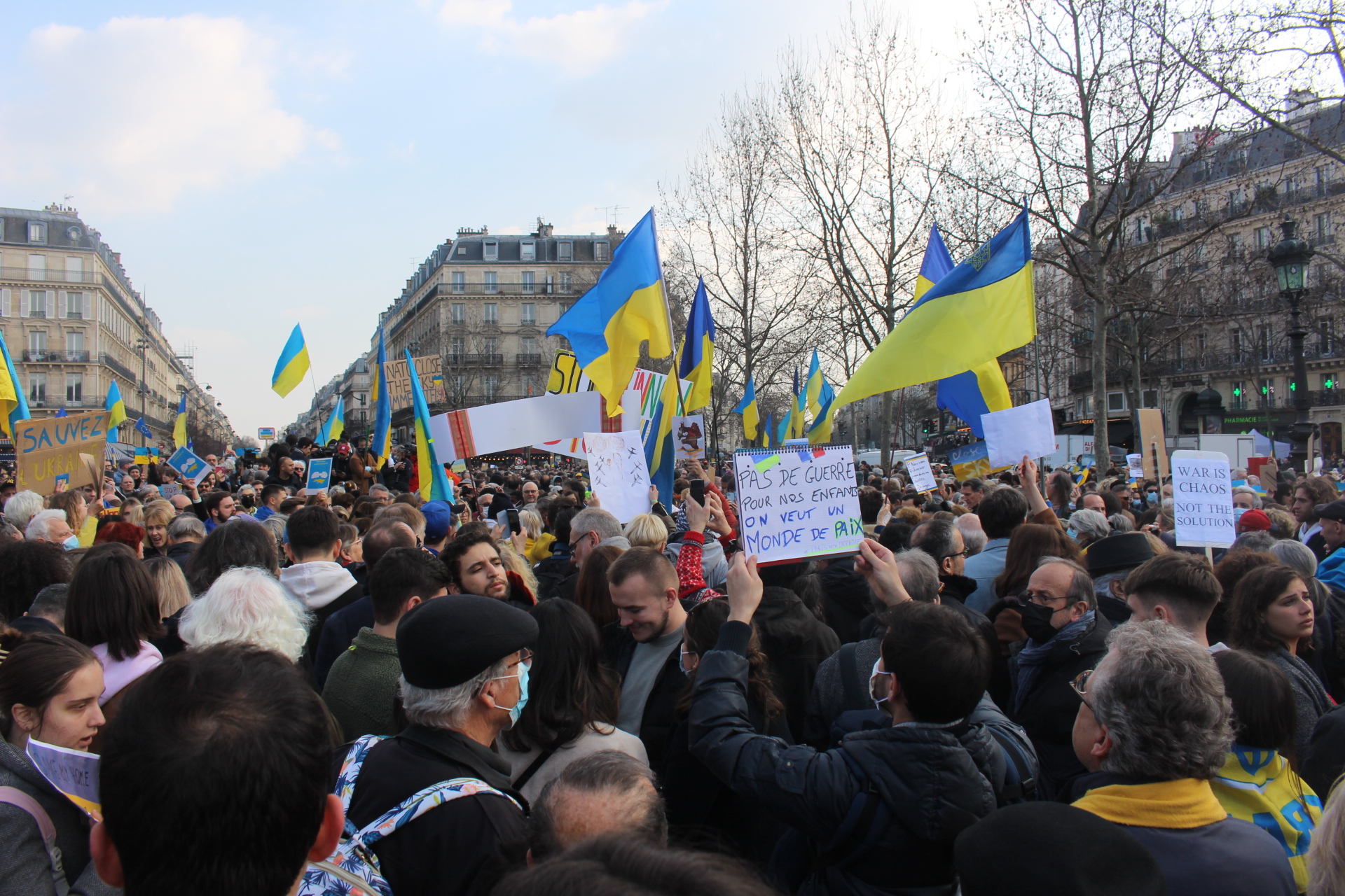 Place de la République à Paris, une foule immense porte des pancartes et des drapeaux jaunes et bleues aux couleurs de l'Ukraine.