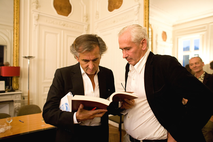 Bernard-Henri Lévy feuillette un livre avec Olivier Corpet.