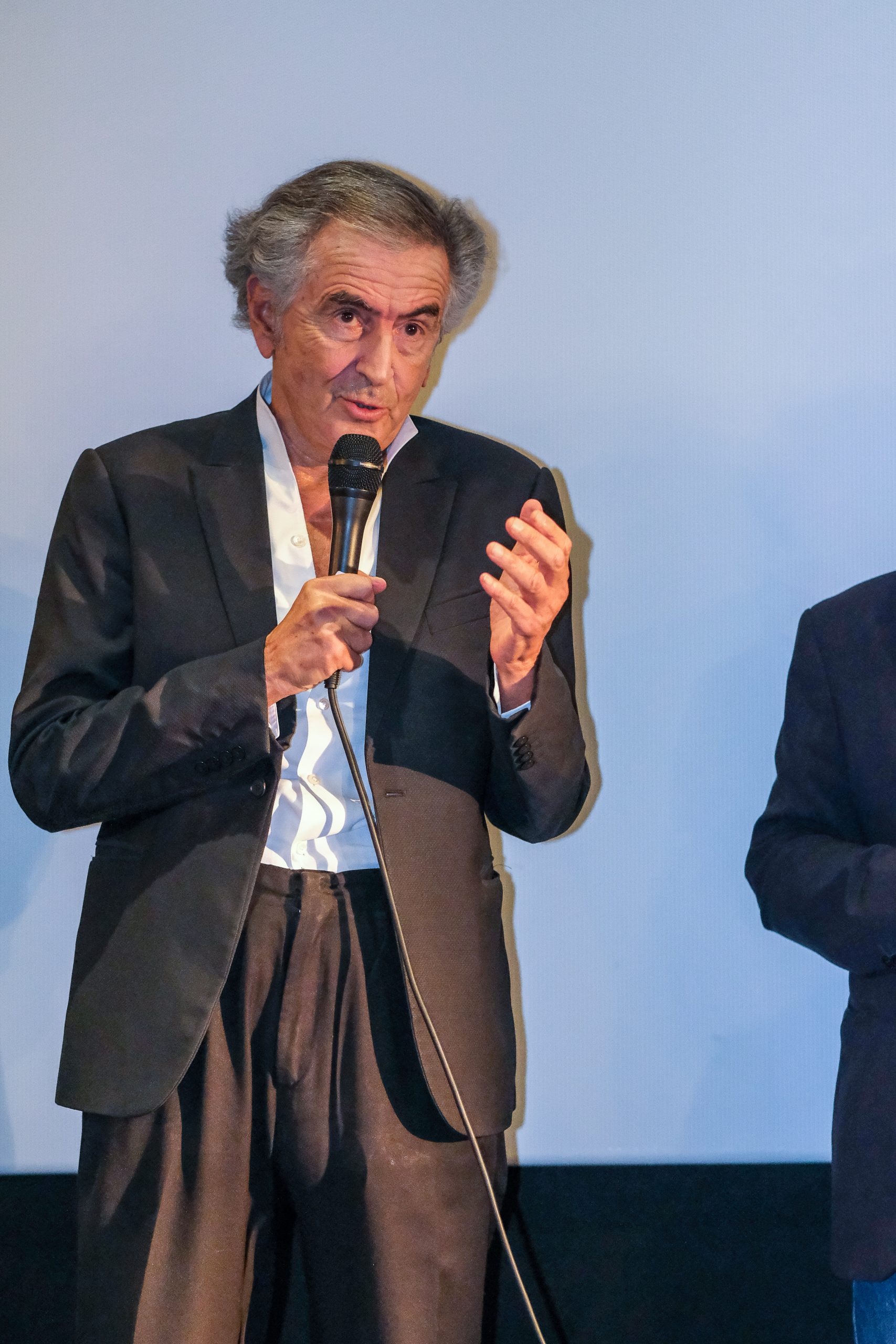 Bernard-Henri Lévy présente son film « Pourquoi l'Ukraine », il parle dans un micro devant un écran de cinéma