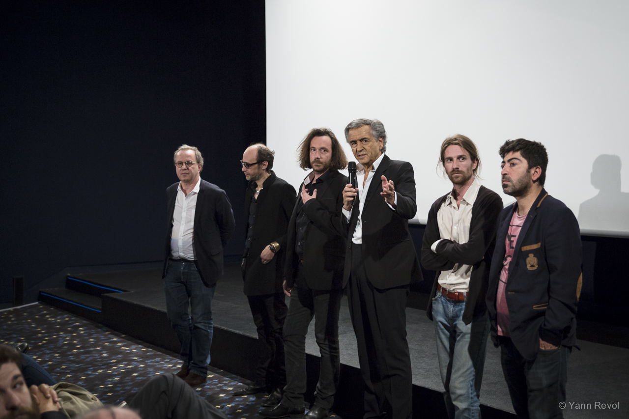 François Margolin, Nicolas Ker, Camille Lotteau, Bernard-Henri Lévy, Olivier Jacquin, Ala Hoshyar Tayyeb, sur la scène du cinéma, devant l'écran. BHL parle au micro.