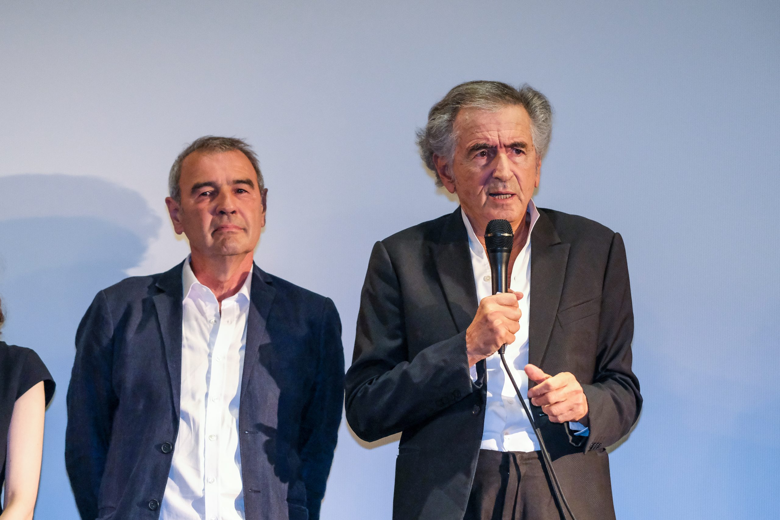 Bernard-Henri Lévy et Marc Roussel parlent devant un écran de cinéma
