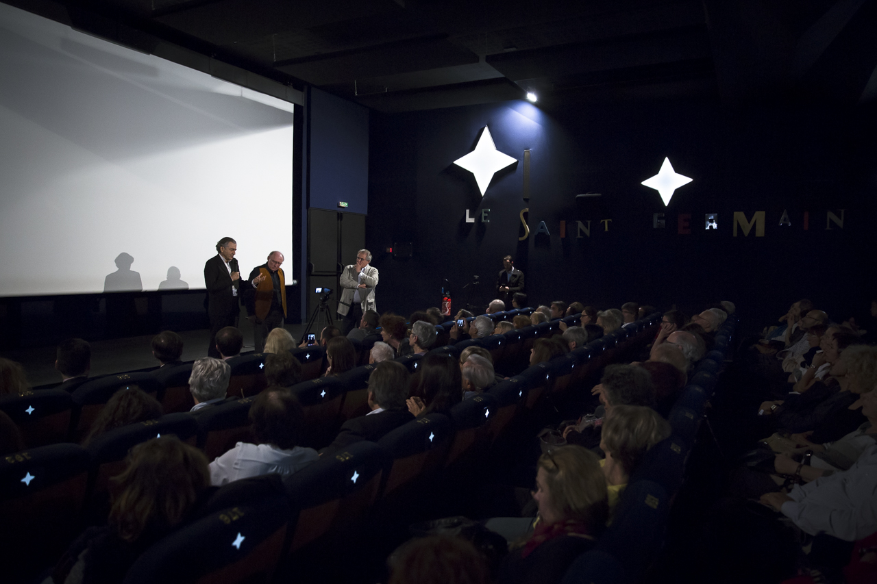 Bernard-Henri Lévy avec Jean-Jacques Moscovitz, et Fred Siksou devant le public d'une salle de cinéma.