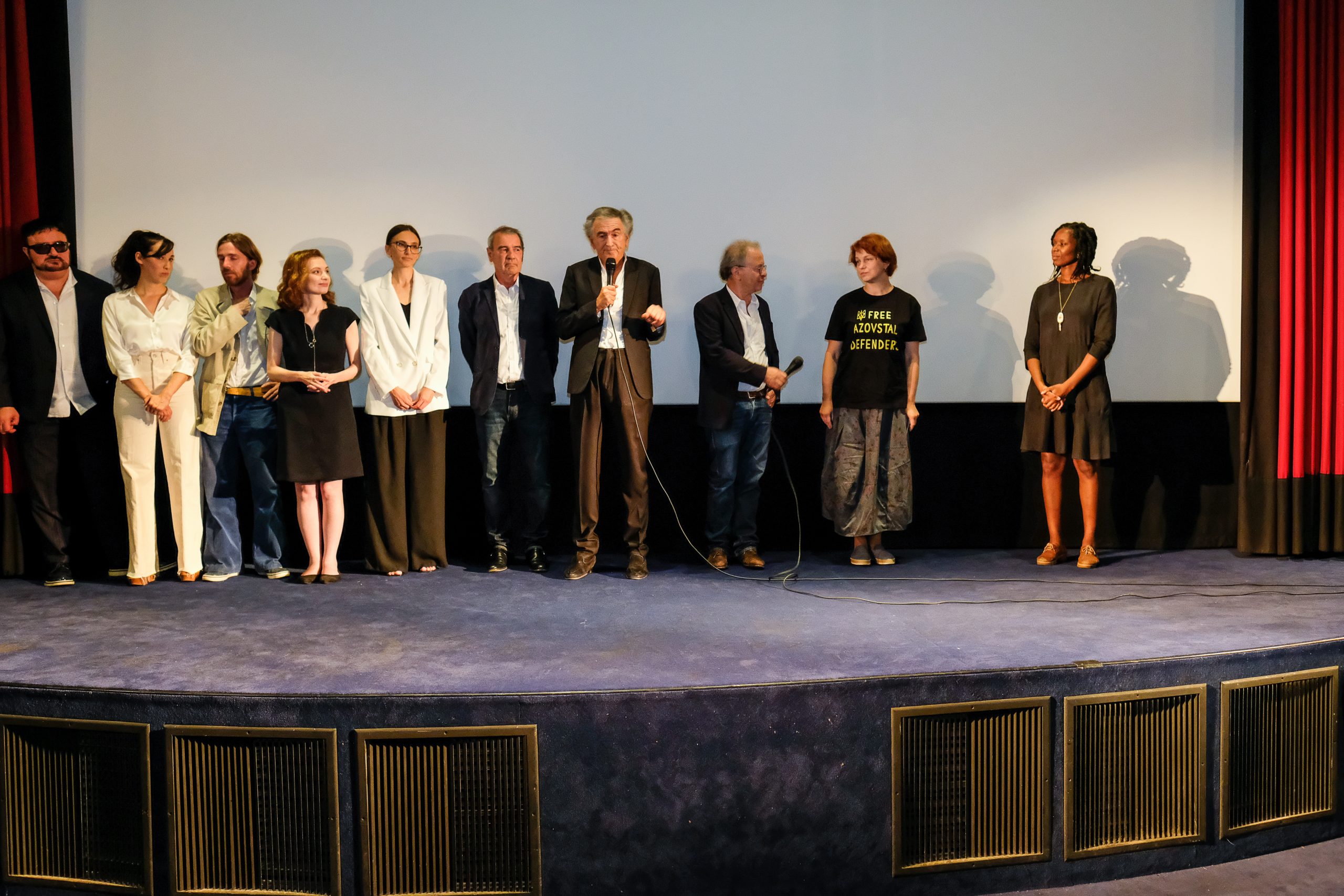 Présentation du film « Pourquoi l'Ukraine » par Bernard-Henri Lévy et toute son équipe, ils parlent devant un écran de cinéma.