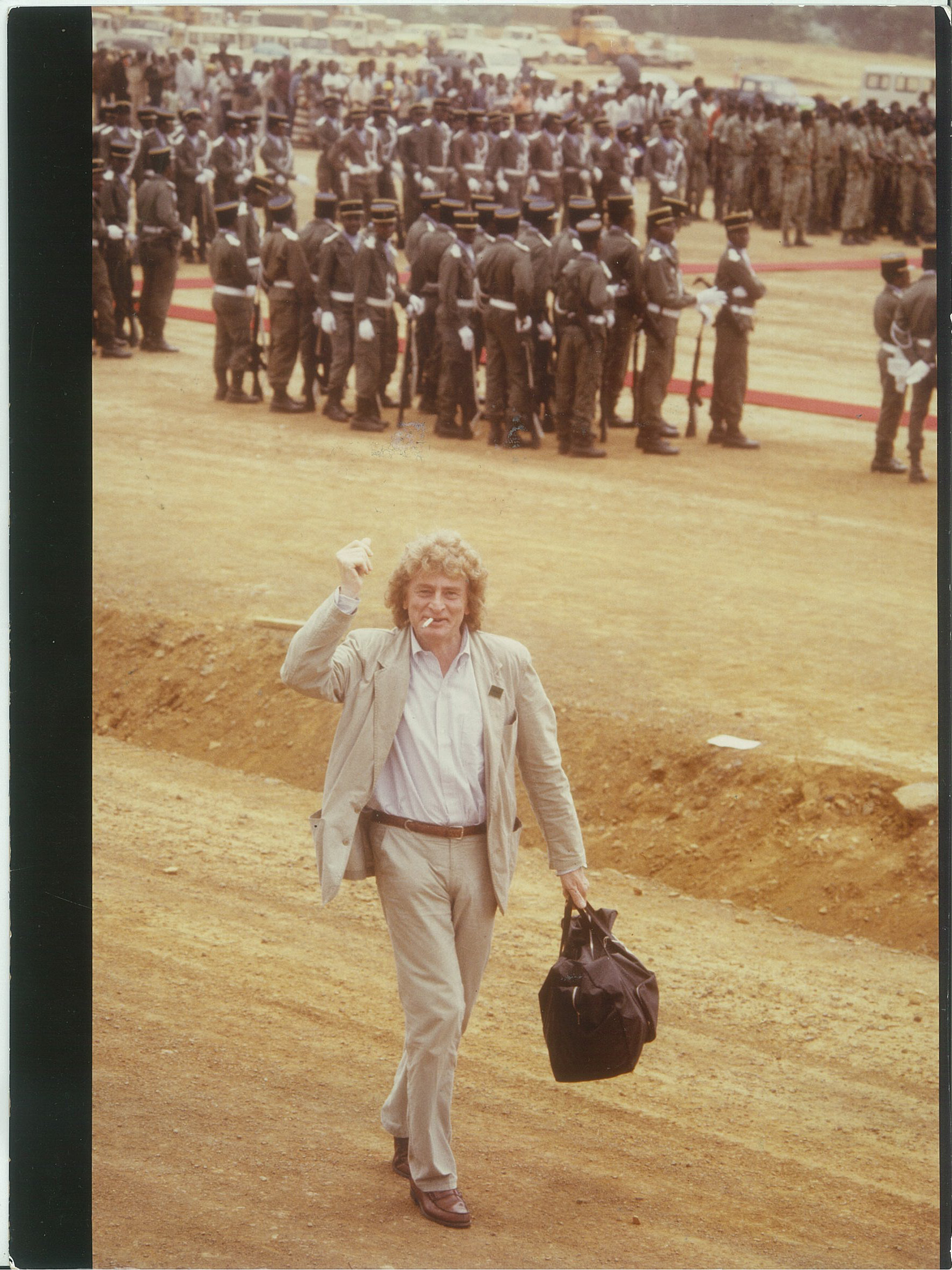 Paul Guilbert marche en levant le point. Derrière lui on voit des militaires gabonais.