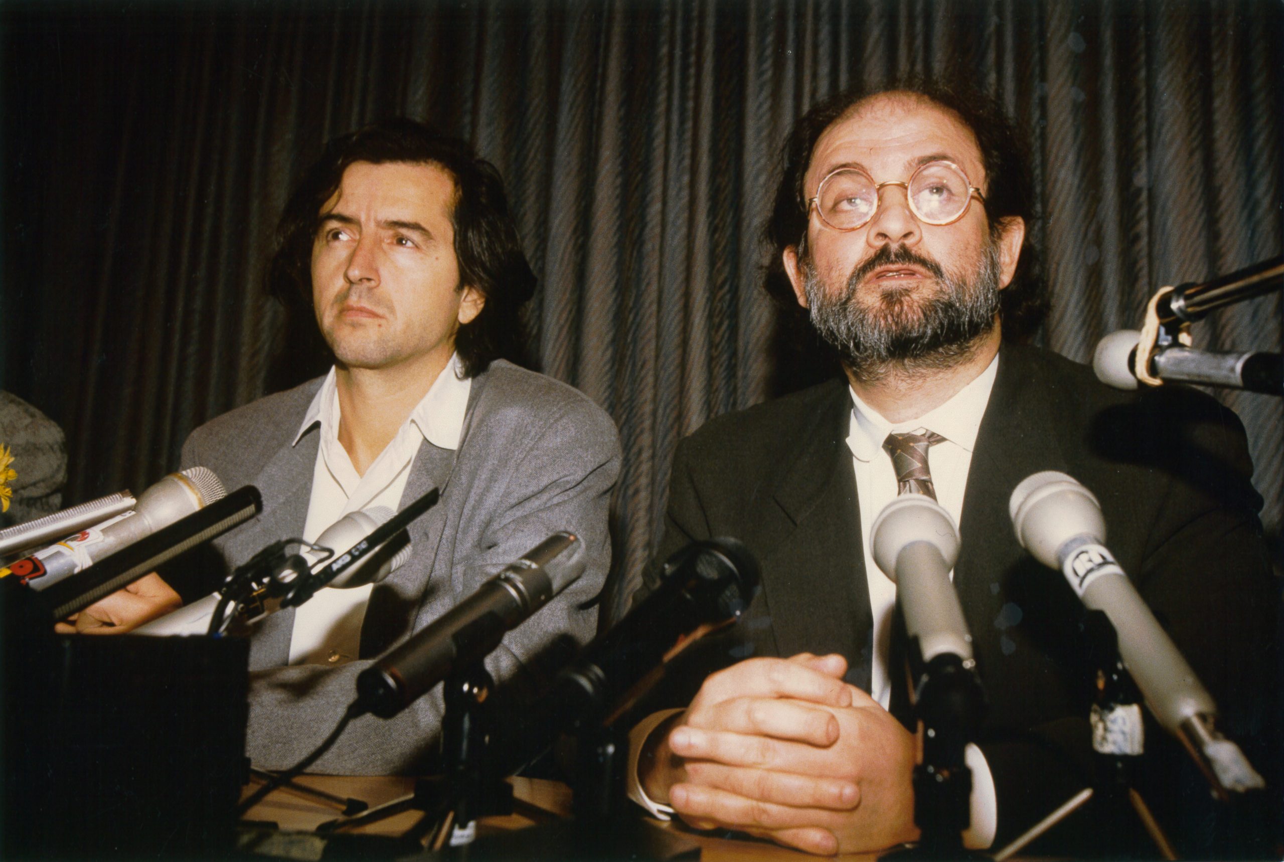 Bernard-Henri Lévy et Salman Rushdie assis derrière des micros posés sur une table.