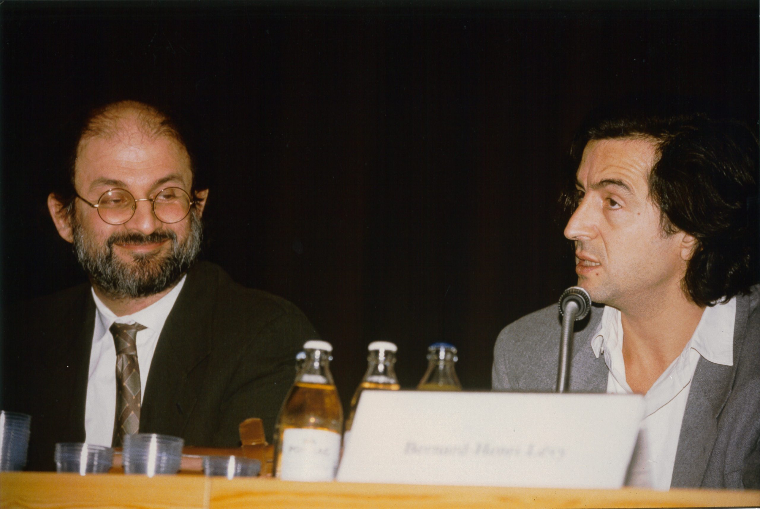 Bernard-Henri Lévy et Salman Rushdie assis derrière une table de conférence.