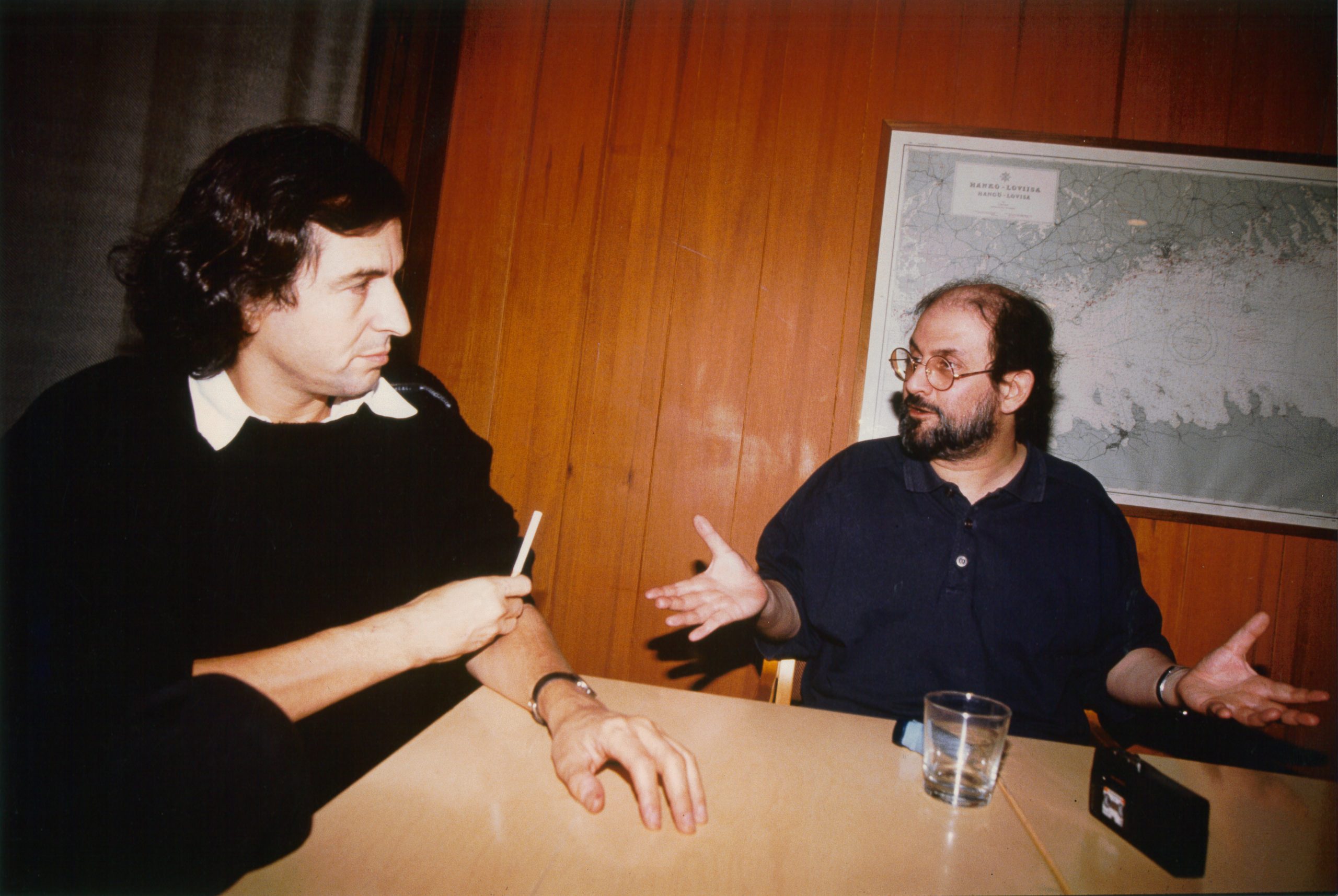 Bernard-Henri Lévy discute avec Salman Rushdie autour d'une table.